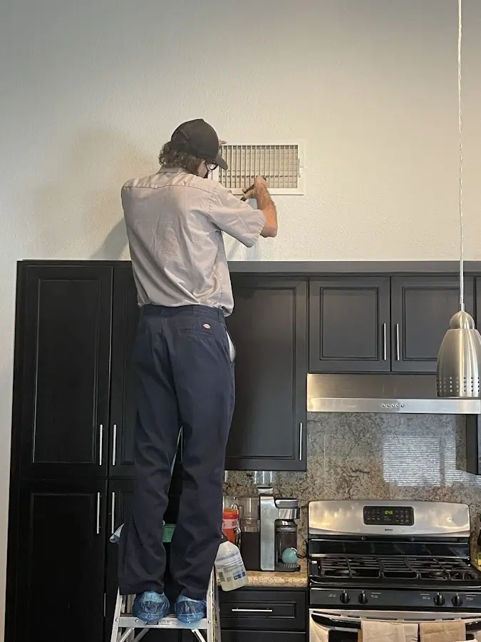 Technician inspecting an air vent during HVAC service in Berlin